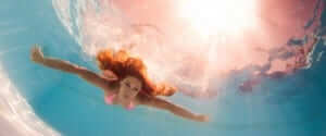 Underwater woman back light portrait in swimming pool.
